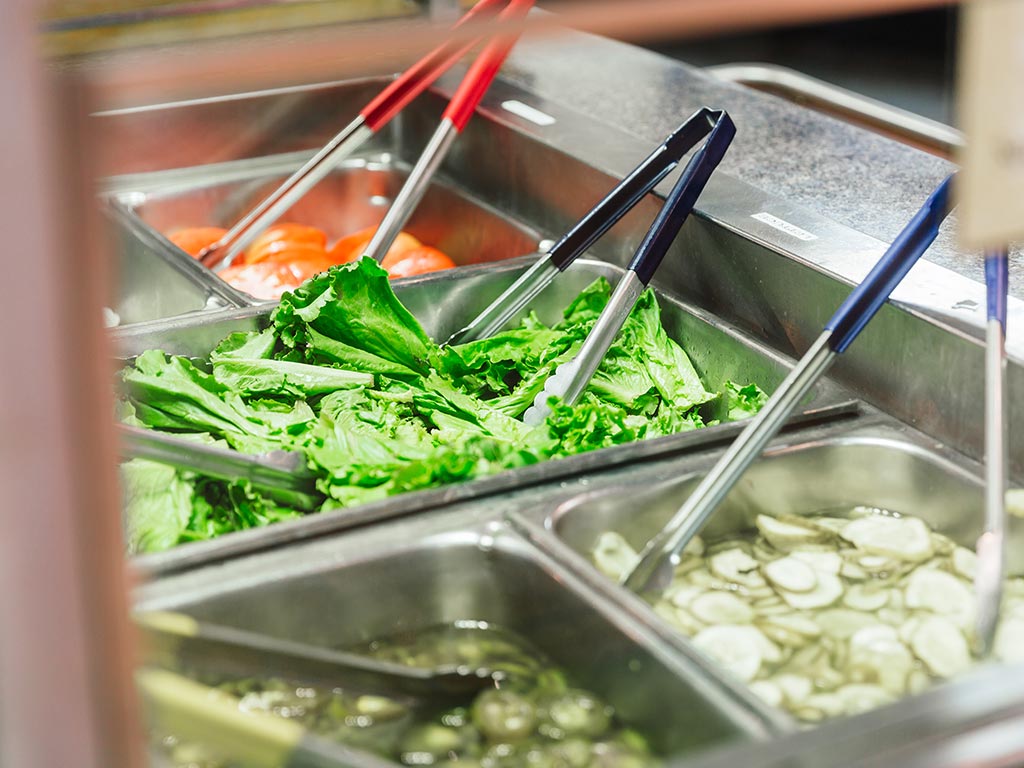 Fresh vegetables in pans at a fast casual airport restaurant