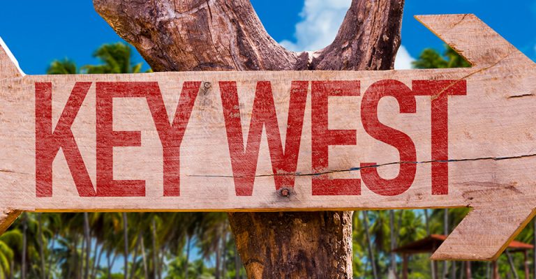 A wooden sign nailed to a tree pointing to Key West